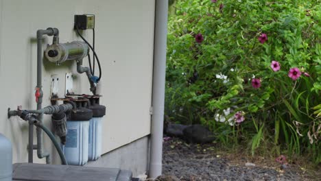 el sistema de filtro de agua fuera de la red visto instalado en el costado de una casa utilizando luz ultravioleta y filtración física e incluyendo una pantalla de monitor digital