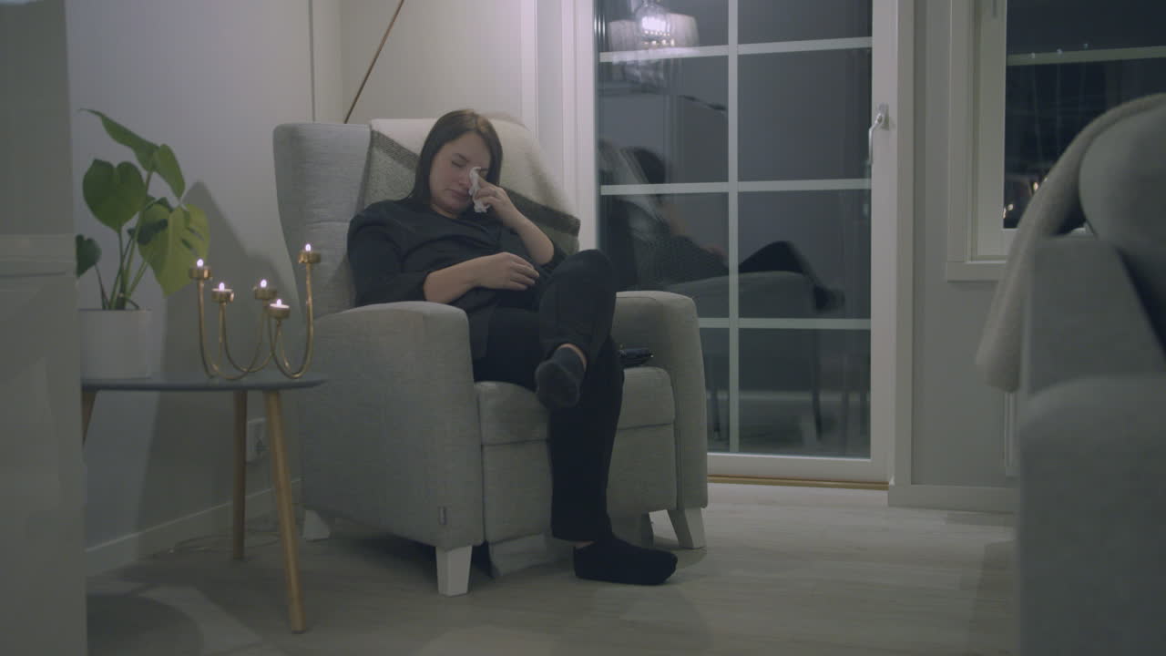 mujer embarazada sentada en un sillón llorando