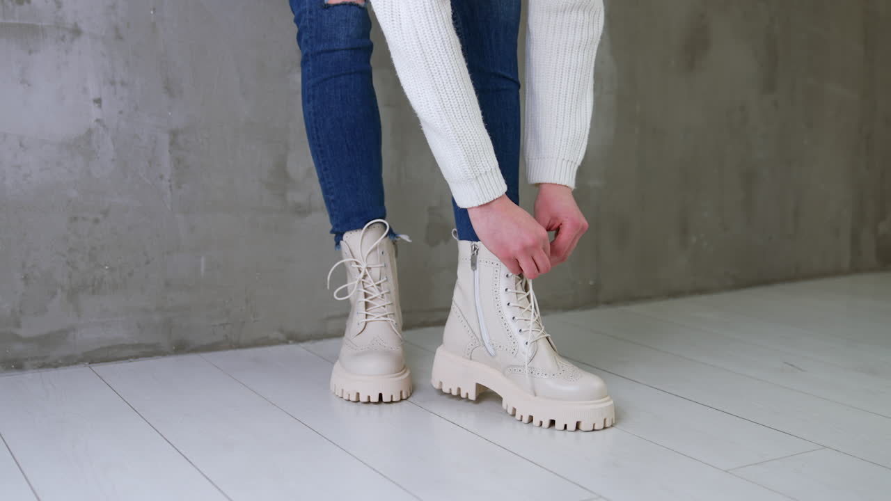 Woman tying laces of cream-colored platform boots