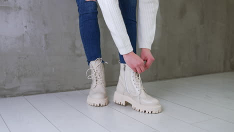 woman tying laces of cream-colored platform boots