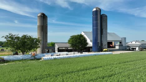 low aerial orbit shot over field at farm in usa with silos