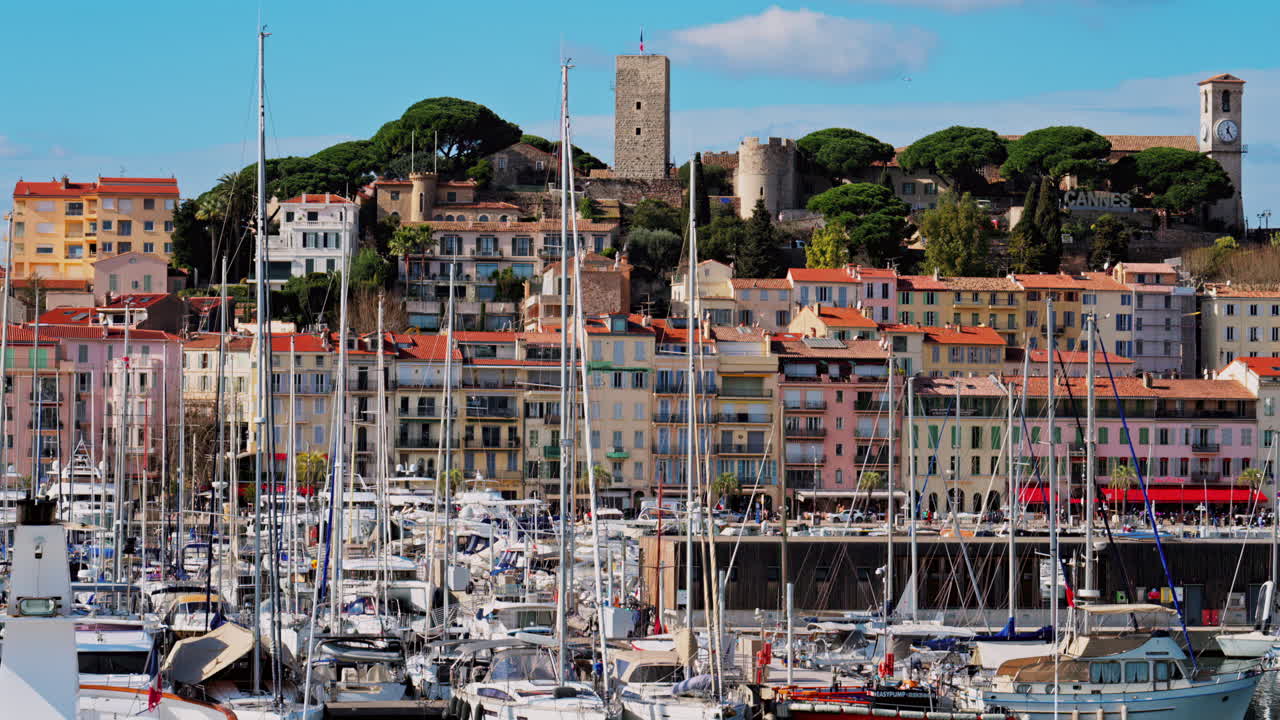 Cannes, France - February 10, 2025: Boats docked in the Cannes Marina with the colourful building of the city on the background