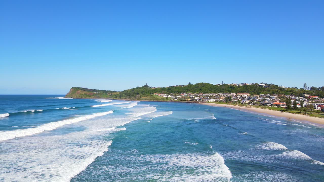 olas que vienen en la orilla arenosa de la playa de siete millas con una vista de la cabeza de lennox - punto de lennox en nsw, australia