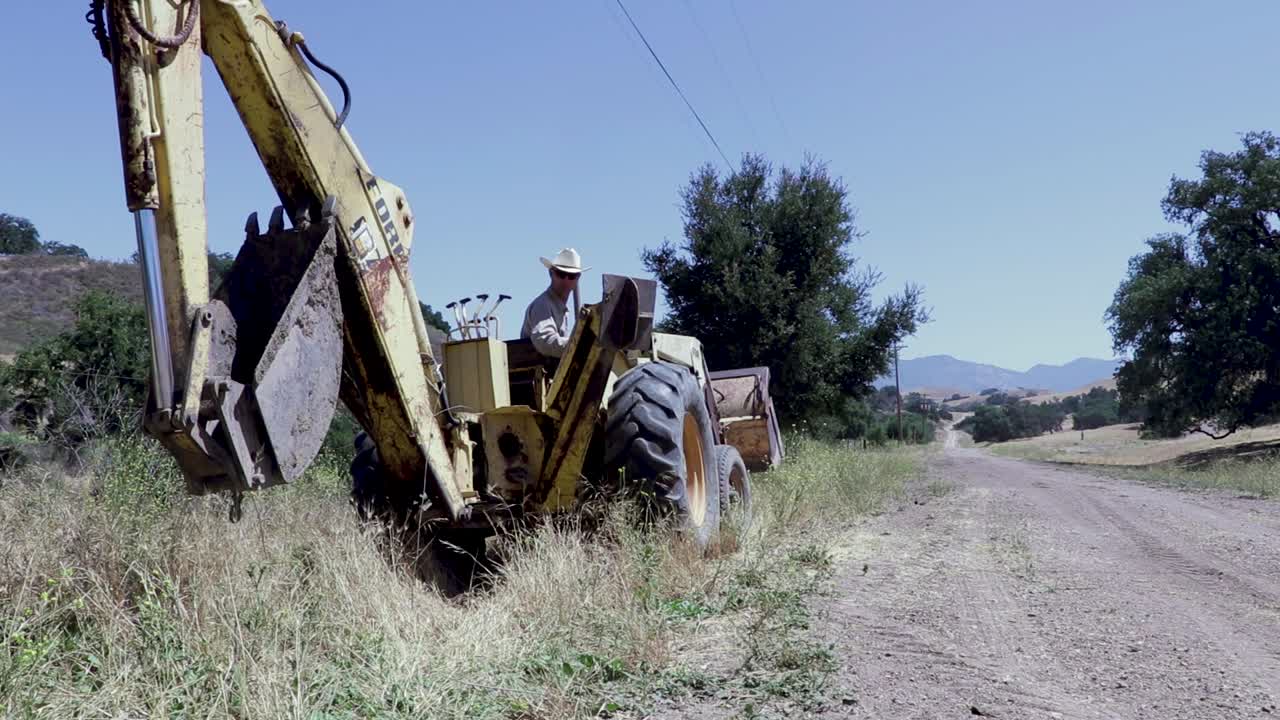 tractor retroexcavadora desenterrando una línea de agua con fugas en un día caluroso-3