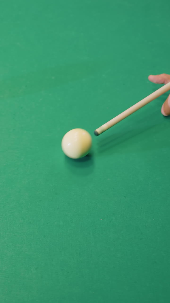 키우 스틱을 사용하여 푸른 빌리어드 테이블에 색 빌리어드의 공을 치고 오렌지색 볼을 겨냥하는 손의 보.