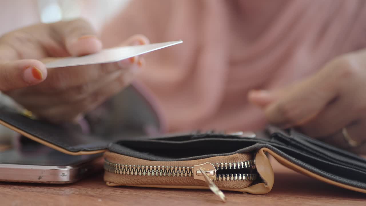 Close-up of hands interacting with a wallet and a card