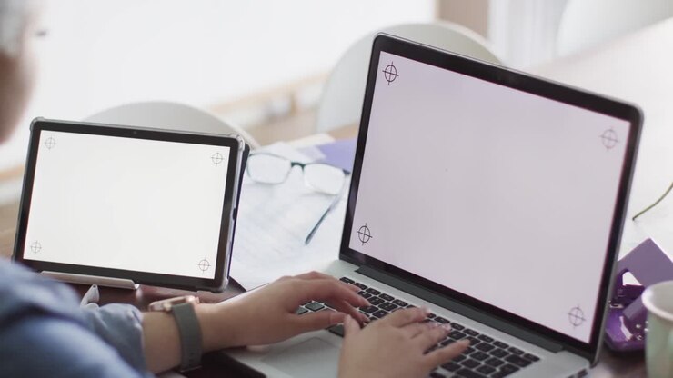 Beschäftigte Frau mit gemischter Herkunft, die zu Hause mit einem Laptop und Tablet arbeitet, mit Platz für Text, in Zeitlupe