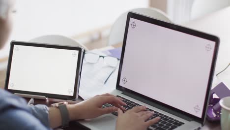 Busy-biracial-woman-working-at-home-with-laptop-and-tablet-with-copy-space-in-slow-motion