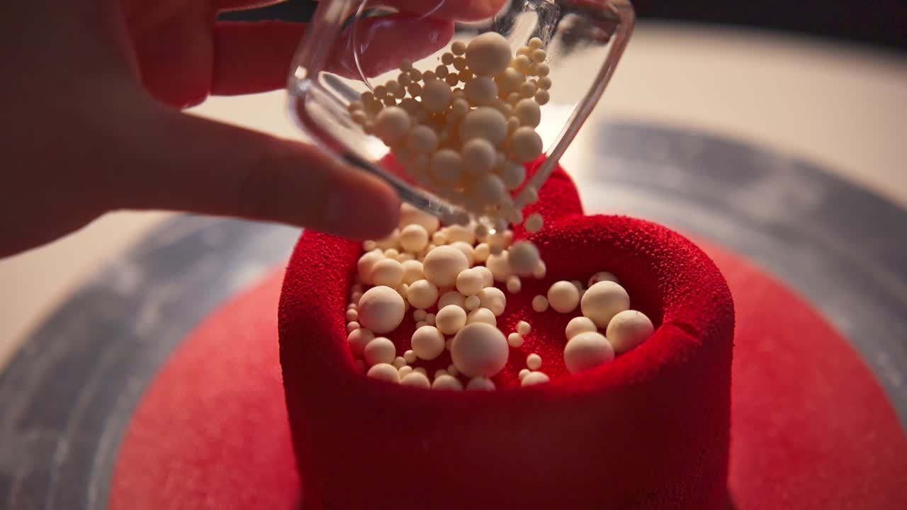 Decorazione di una torta rossa a forma di cuore con codette bianche