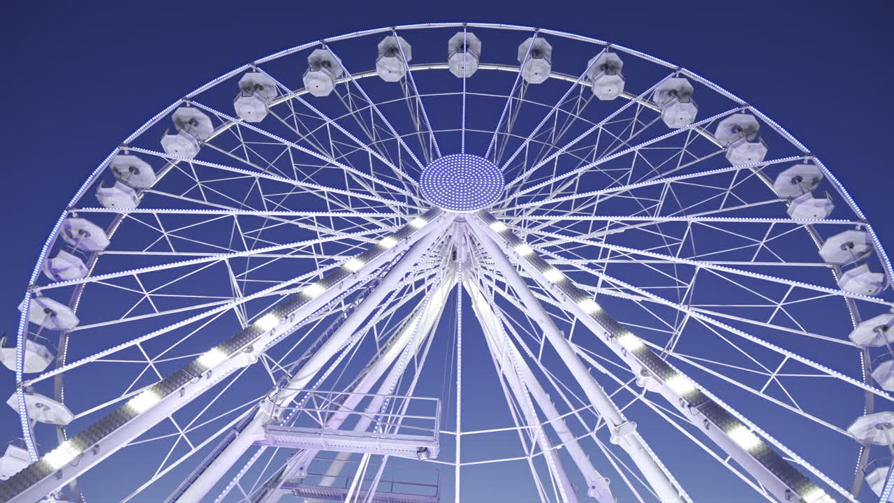 View of white, illuminated ferris wheel rotating with the sky on the background in Antibes, France
