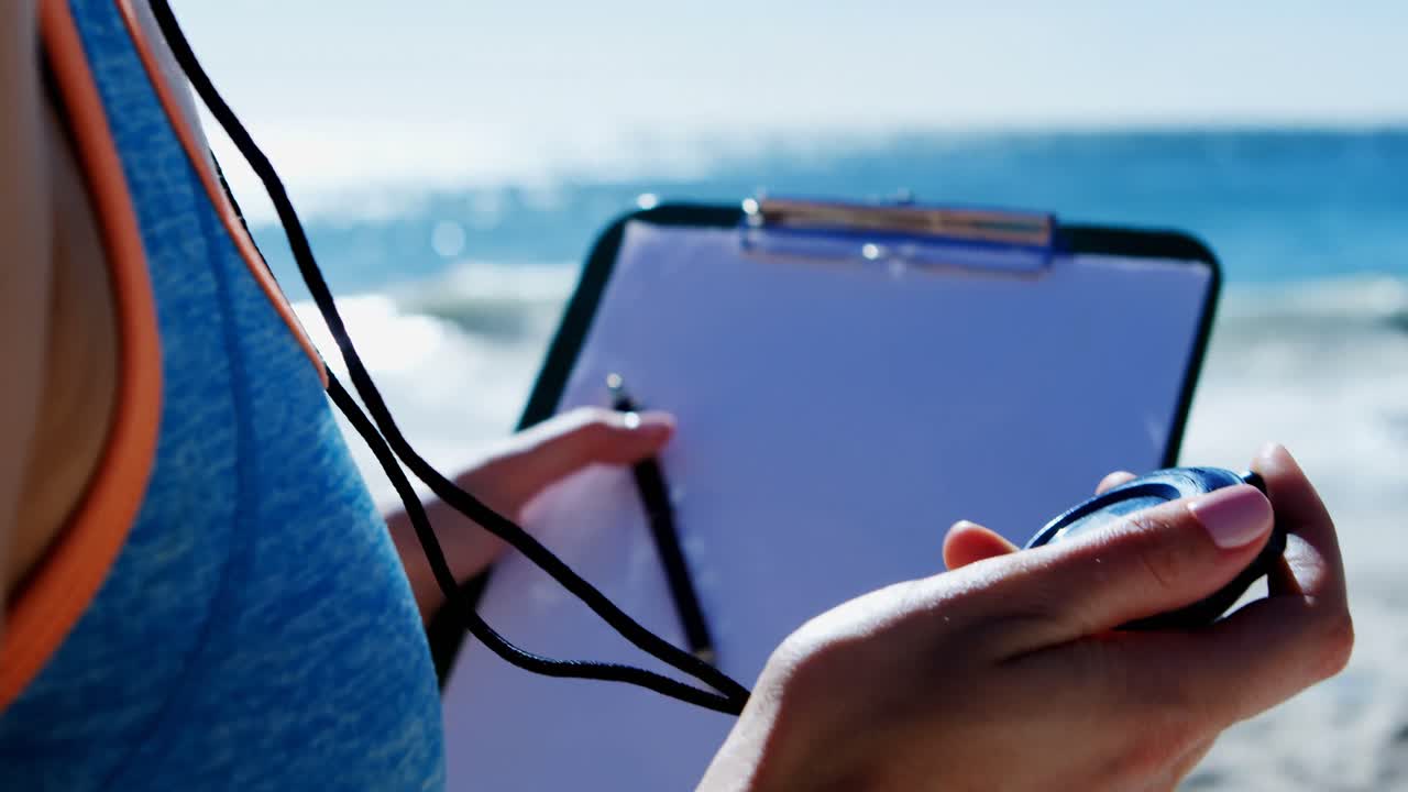 entrenadora de voleibol femenina con un cronómetro y un clipboard 4k