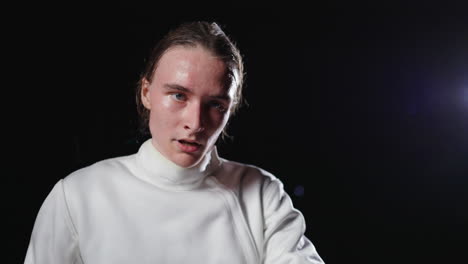 a man in a fencing mask and uniform holds a foil sword