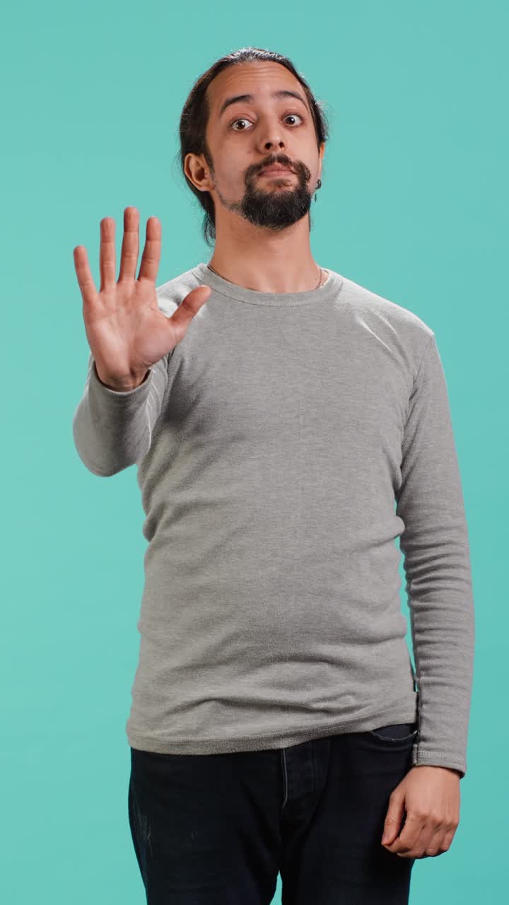 Vertical video Assertive man doing stop hand gesture sign