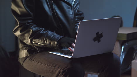 criminal wearing bandit mask typing on laptop, then closes it and puts it away