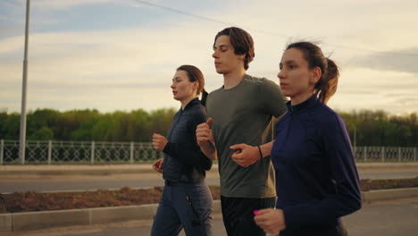 Personas-Atléticas-Corren-En-Una-Mañana-De-Verano,-Dos-Mujeres-Jóvenes-Y-Un-Hombre-Entrenan-Juntos