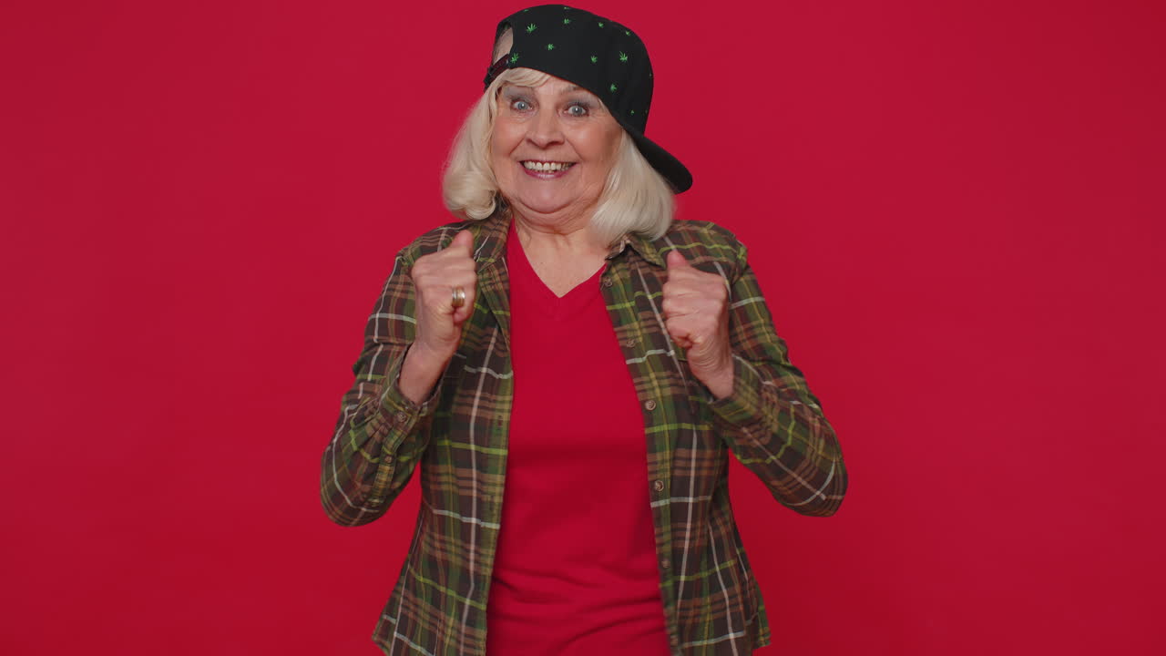 Elegante anziana signora in camicia che urla e alza i pugni nel gesto 'Ce l'ho fatta!', celebrando il successo.