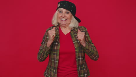 elegante mujer de edad avanzada en camisa gritando levantando los puños en gesto lo hice celebrando el éxito ganando