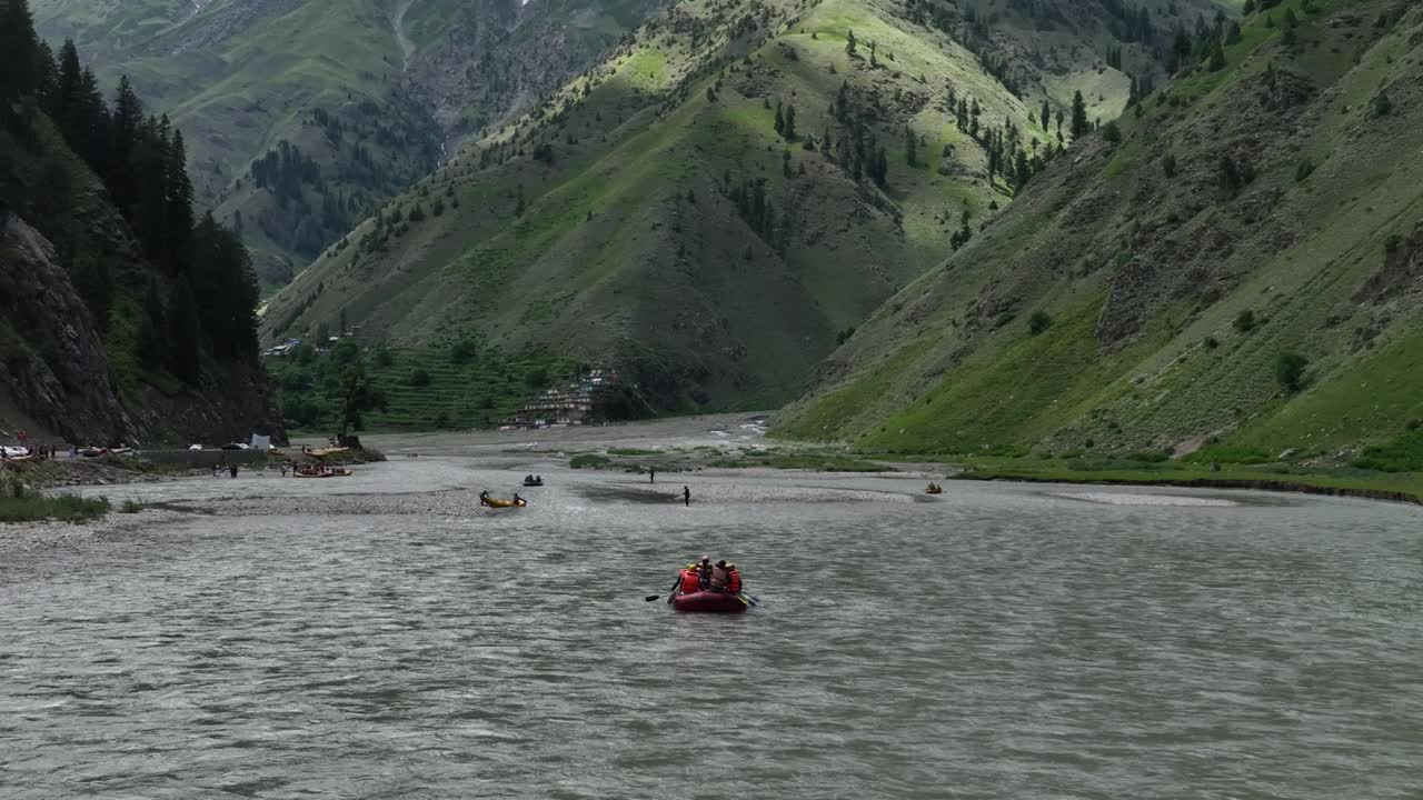 Il drone sorvola i rafters che navigano le vivaci acque blu di Naran, con l'inquadratura che si allarga gradualmente per rivelare lo scenario mozzafiato di montagne imponenti