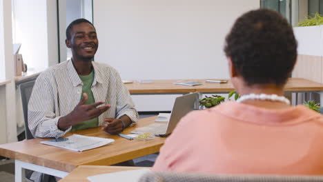 Muslim-Young-Worker-Sitting-On-The-Table-While-Talking-With-Businesswoman