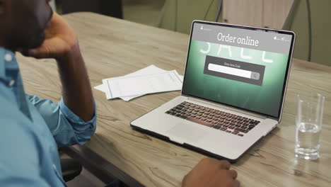 African-american-man-using-laptop,-online-shopping-during-sale,-slow-motion