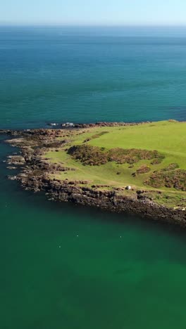 descending social ratio aerial video of brown's bay on the causeway coastal route on a bright and sunny day. filmed in 1080x1920 social ratio, in 60fps and with rec709 color
