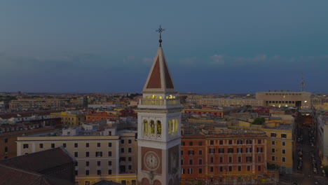 Circular-footage-of-beautiful-tower-with-clocks.-Church-and-apartment-buildings-in-background.-Historic-city-at-twilight.-Rome,-Italy