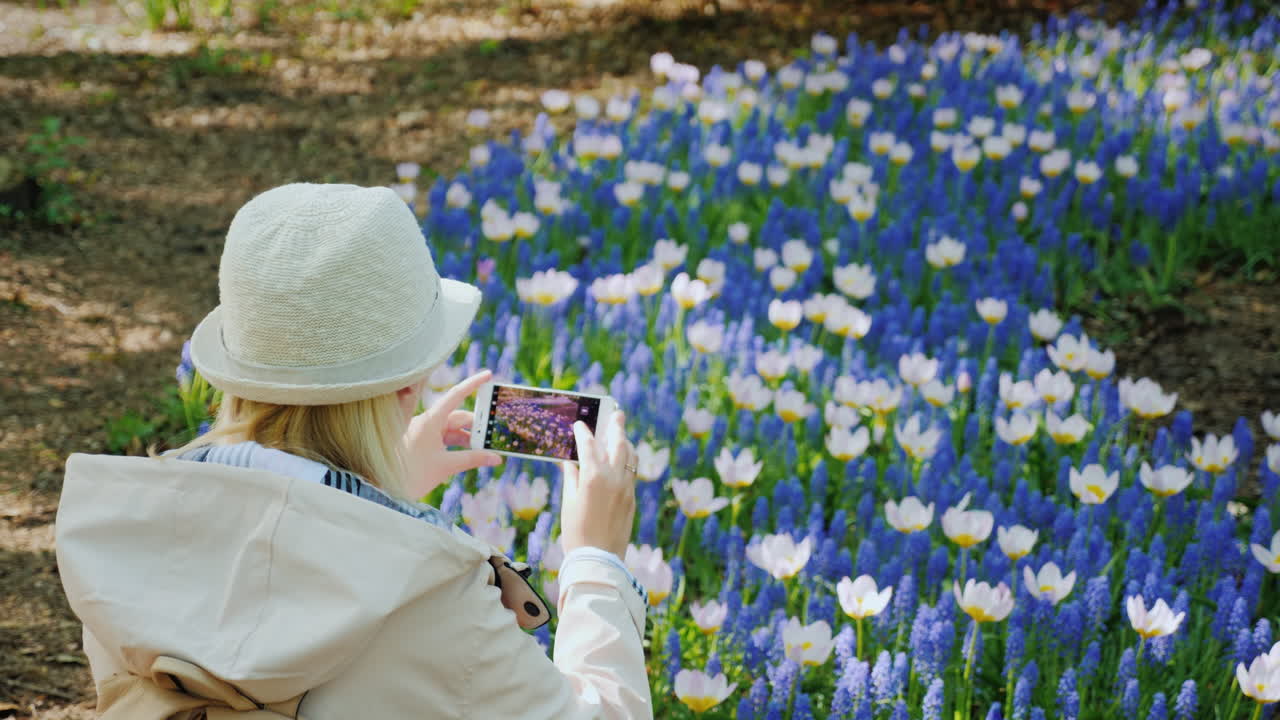 mujer joven toma fotos de flores de primavera