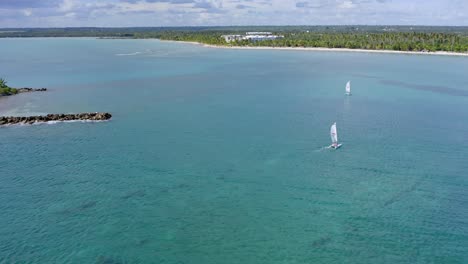 Aerial-orbit-shot-of-Catamaran-Sailing-over-exotic-Caribbean-Sea-towards-Playa-Nueva-Romana-on-Dominican-Republic