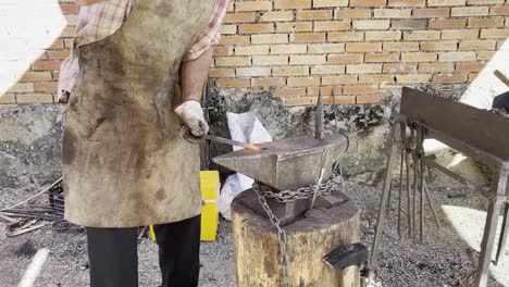 black smith quickly hammers hot red metal rod against anvil at arts festival