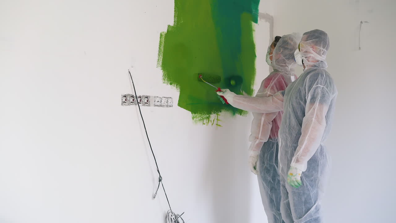 mujer y hombre vestidos con trajes de trabajo llegan a la pared con mancha