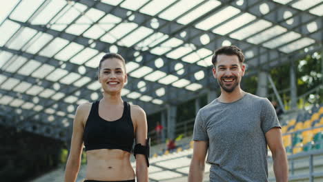 young jogger couple giving five to each other and smiling to the camera after running training time