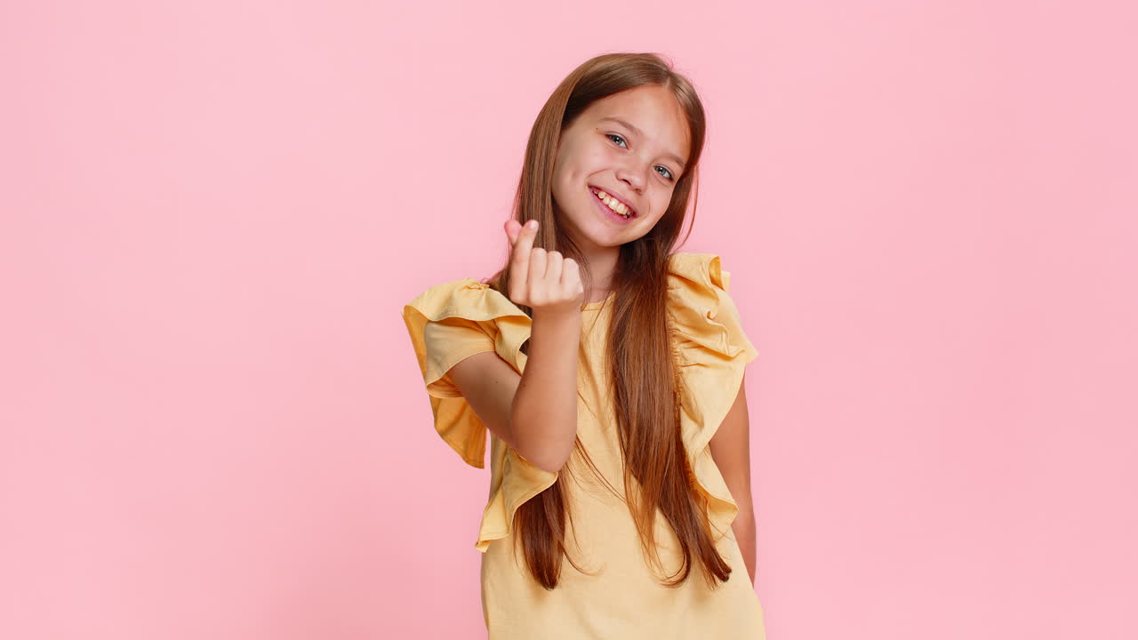Child girl kid making heart gesture with fingers while smiling to express love friendship emotion