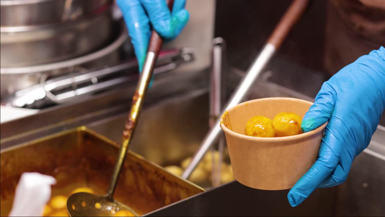 manos con guantes sirviendo albóndigas en un cuenco