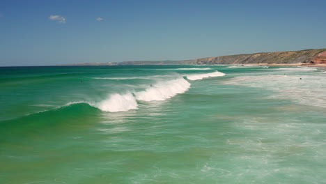 Aerial:-Surfing-the-beach-of-Bordeira-in-the-Algarve,-Portugal