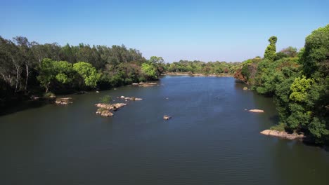 Drone-flying-over-a-river-with-trees-on-both-sides