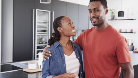 Happy-african-american-couple-talking-and-embracing-in-kitchen,-slow-motion