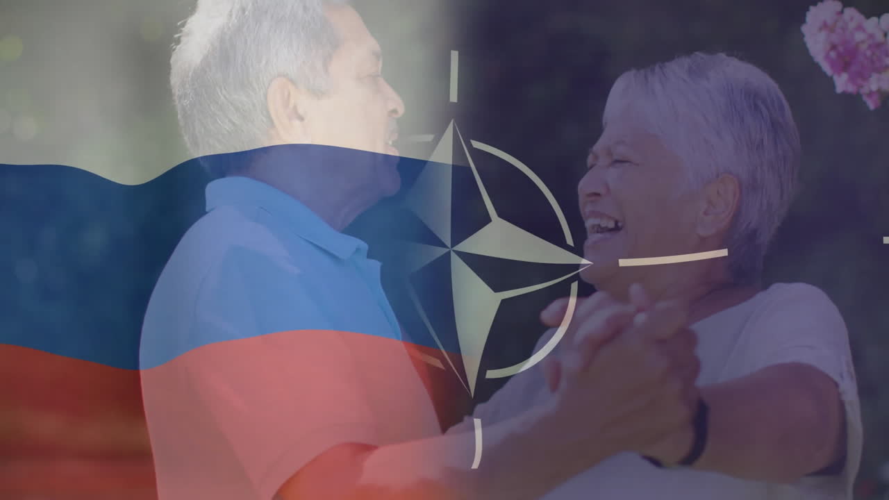 Dancing with Russian flag and NATO symbol overlay, elderly couple celebrating