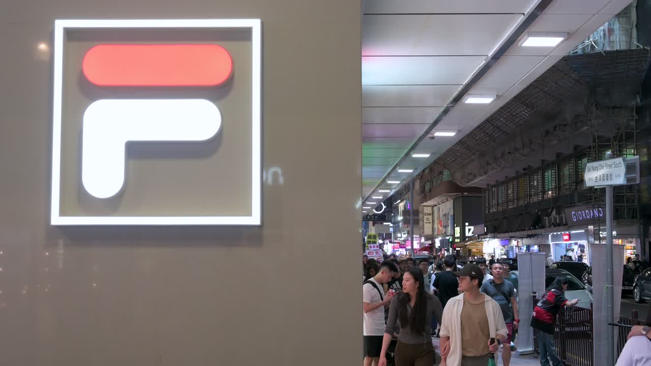 Chinese pedestrians walk past a Fila store and logo, an Italian sporting goods brand, in Hong Kong.