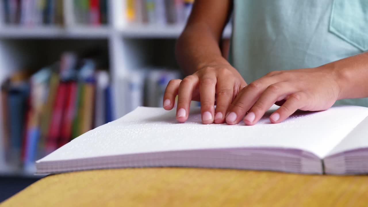 sección media de un niño de escuela leyendo un libro en braille en el aula de la escuela