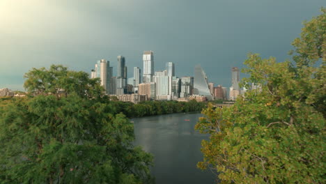 golden hour aerial shot flying in reverse away from downtown austin, passing over ladybird lake and zilker park. moody skies, soft light, and detailed architecture create a cinematic cityscape