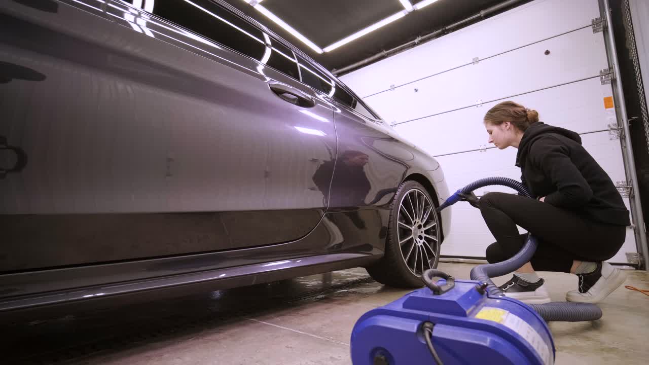 한 여성이 새로 은 검은 차에서 공기로 물을 고 있습니다.