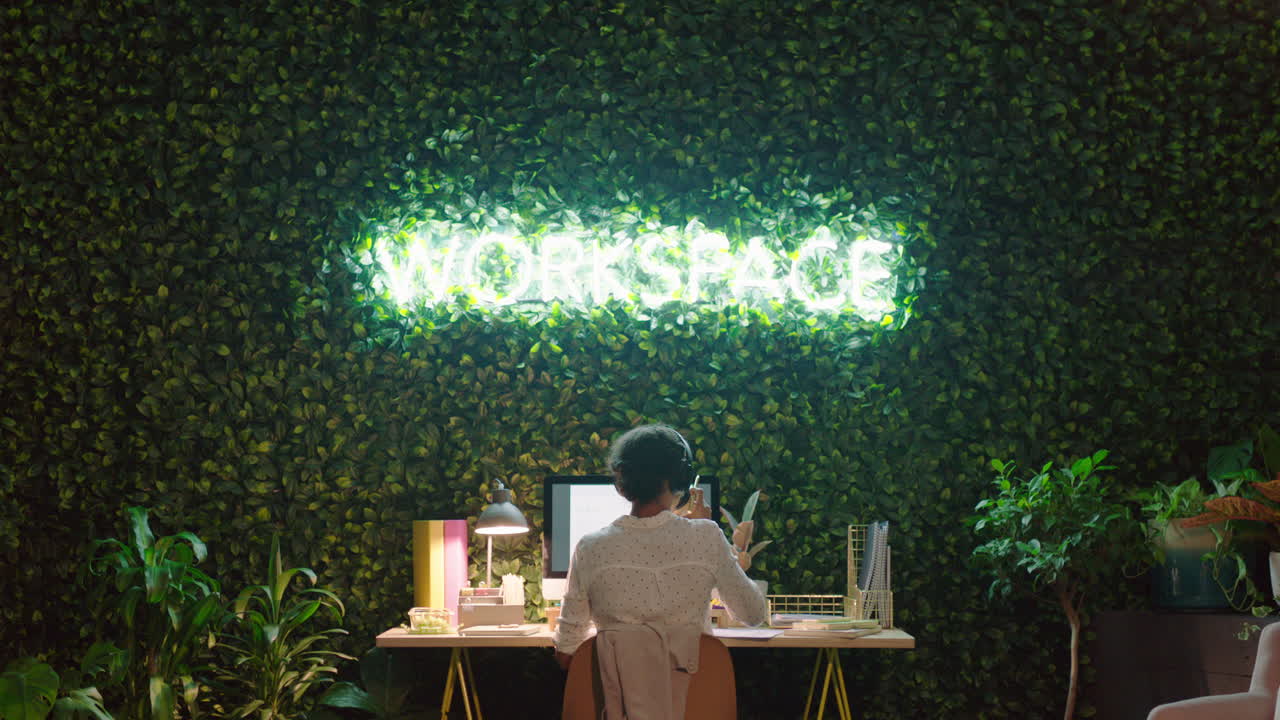 mujer de negocios que trabaja hasta tarde usando la computadora navegando por los datos haciendo lluvia de ideas planeando el proyecto fecha límite escuchando música usando auriculares en la oficina por la noche