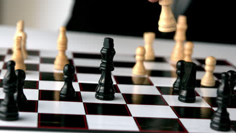 white chess piece knocking over a black one