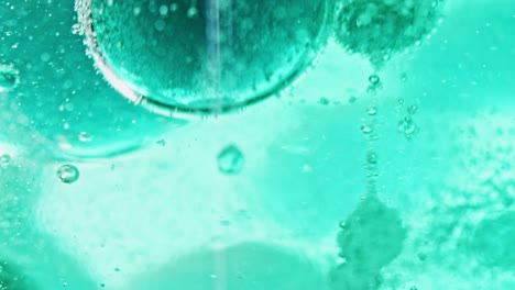 macro shot of big and small blue bubbles floating and dripping in bright blue water