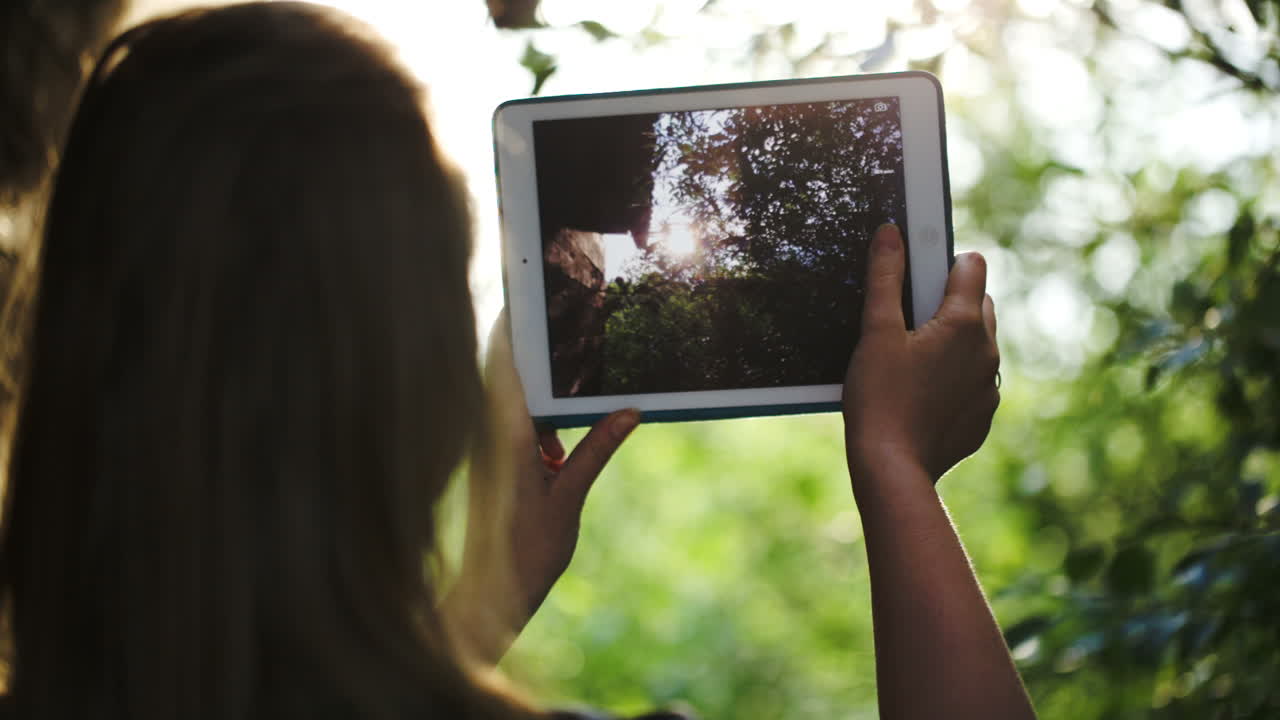 mujer tomando fotos de la naturaleza con una computadora tablet