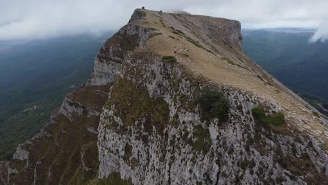 girl running on the top of a dangerous mountain, practicing trail running or skyrunning, incredible views of the cliff