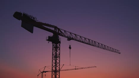 La-Cámara-Se-Mueve-Hacia-Las-Grúas-De-Construcción-Con-Pájaros-Al-Atardecer