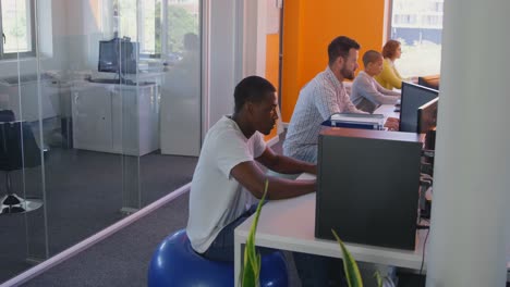 side view of mixed race business team working on desktop pc at desk in modern office 4k