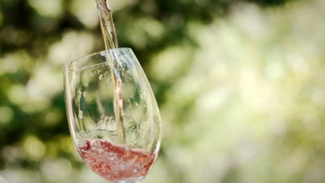 Ein-Glas-Roséwein-Vor-Grünem-Hintergrund-In-Zeitlupe-Einschenken