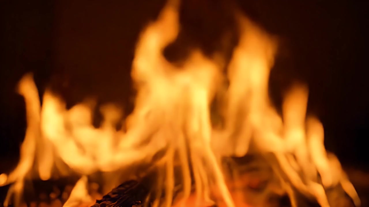 Primo piano di fiamme arancioni brillanti che bruciano in un camino